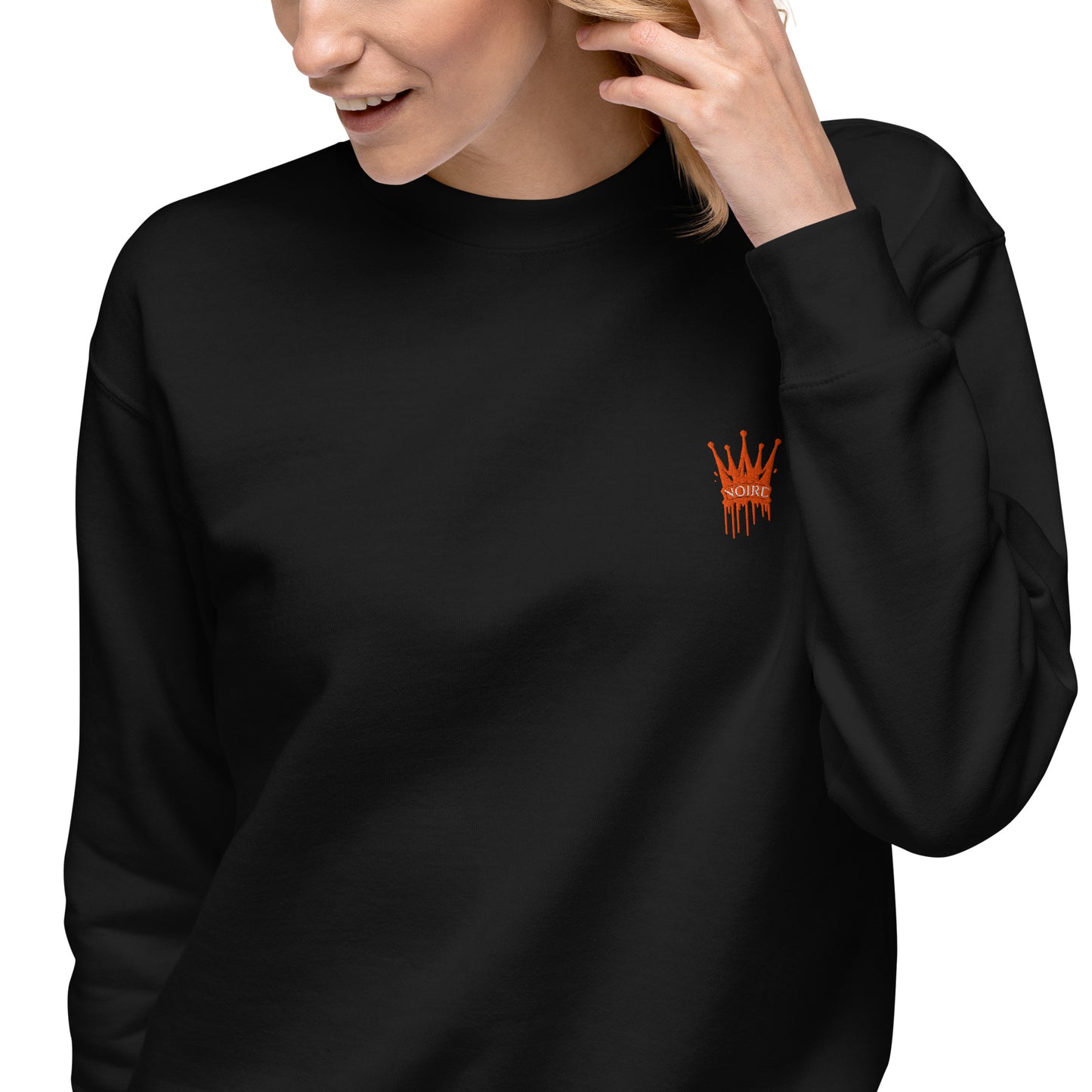 Black edgy embroidered crewneck sweatshirt with small orange crown logo on chest worn by woman