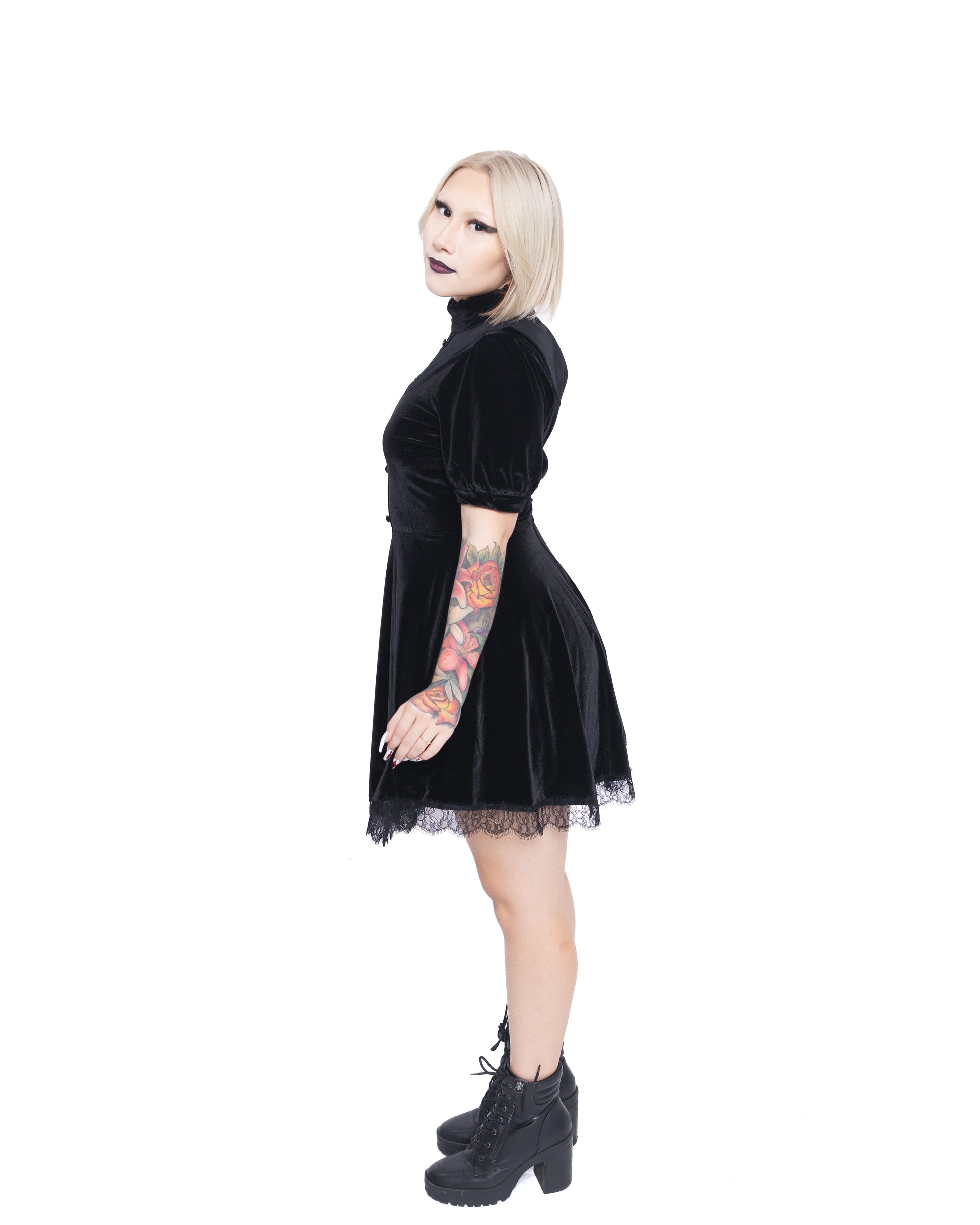 Woman wearing a short sleeve gothic dress for women in black velvet with lace trim and high collar