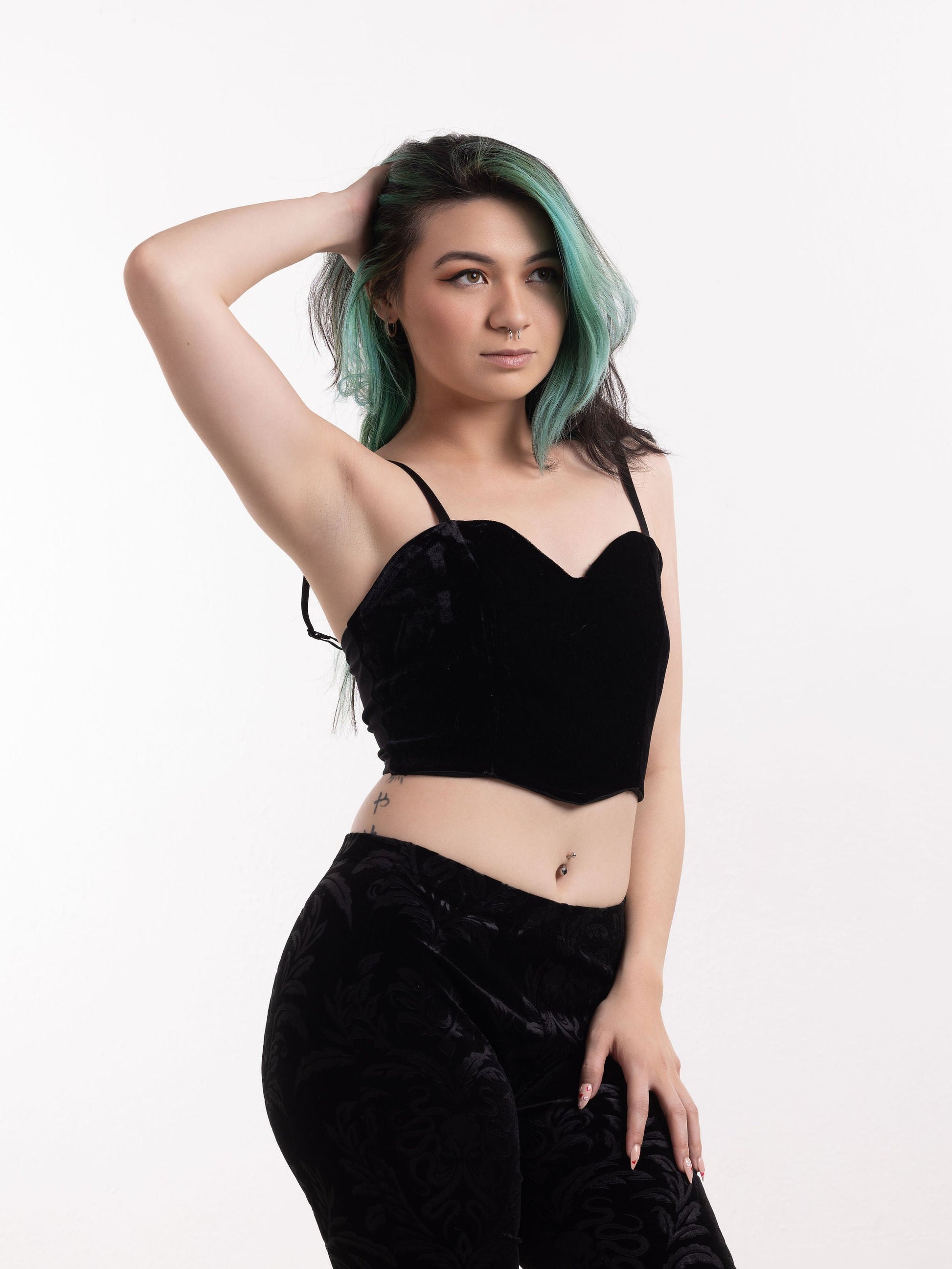 Young woman wearing black gothic velvet cami and matching pants with green hair posing